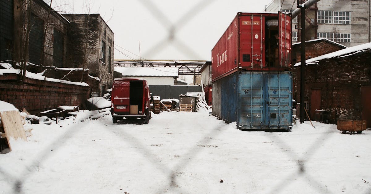 Shipping containers and a van in a snow-covered industrial yard