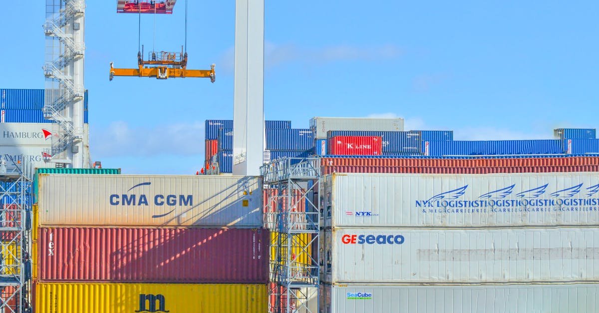 Crane lifting a container over stacked CMA CGM and GE SeaCo containers at a terminal
