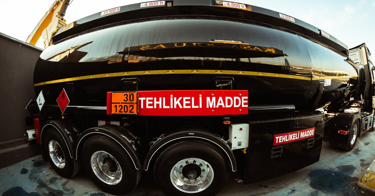 Large black tanker truck with hazardous material signs and Turkish 'TEHLİKELİ MADDE' labeling on the rear, carrying dangerous goods.