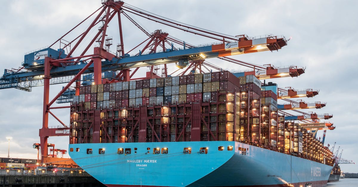Large blue container ship at a busy port with towering red cranes unloading multi-colored shipping containers onto the dock?