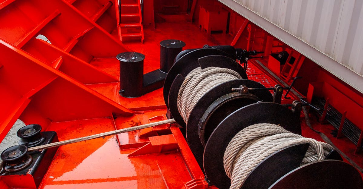 Heavy-duty winch drums with coiled steel rope on a red industrial deck view close-up