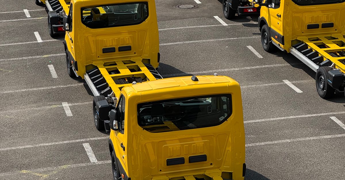 Top-down view of three yellow tow trucks parked in a lot along diagonal lines of parking spaces.