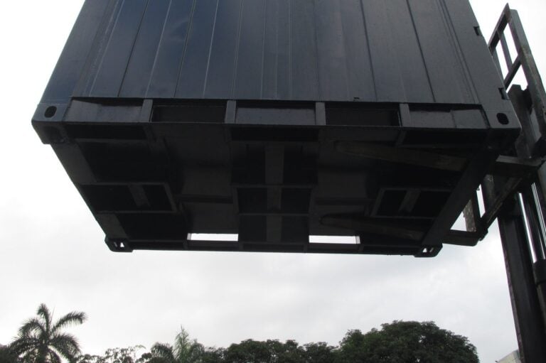 Black QuadCon container lifted by a forklift, showing the fork pockets